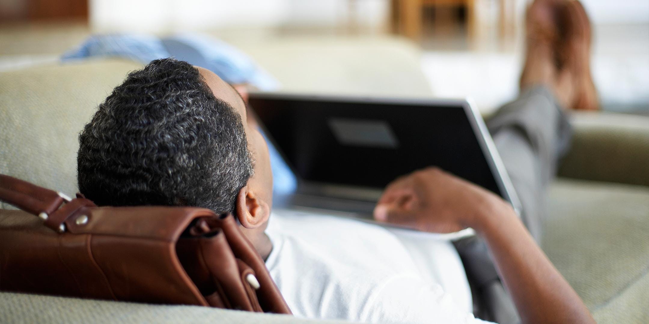 man relaxing on couch with laptop