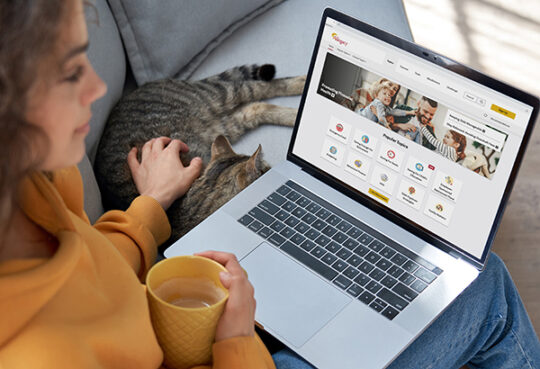 woman with coffee mug sitting on couch petting cat with laptop open to Allegacy Enrich learning platform