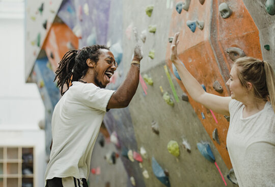 Young Adults at an indoor rock climbing wall giving a high-five