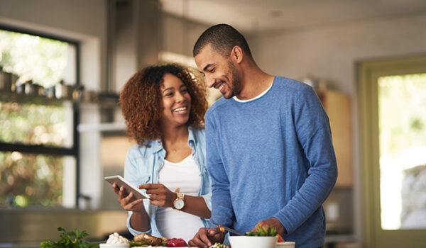 Shot of a happy young couple using a digital tablet while preparing a healthy meal together at home