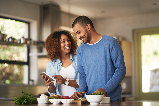 Shot of a happy young couple using a digital tablet while preparing a healthy meal together at home