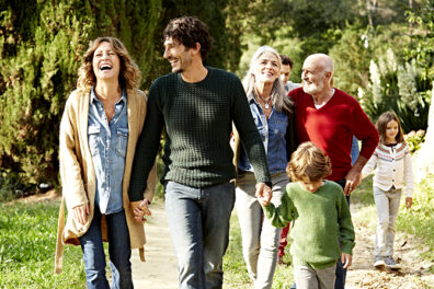 multi-generation family holding hands while walking in park