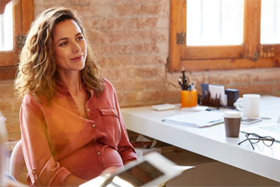 contemplative woman sitting in sunny modern office with coffee and glasses nearby