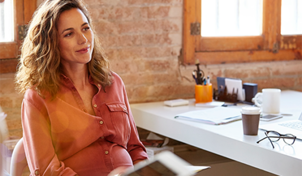 contemplative woman sitting in sunny modern office with coffee and glasses nearby