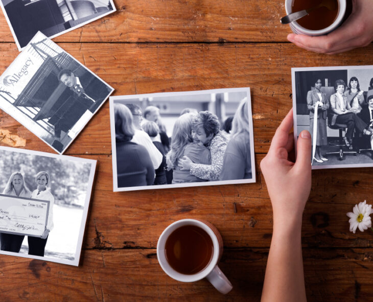 close up of hands looking at old black and white photos of Allegacy employees from decades past