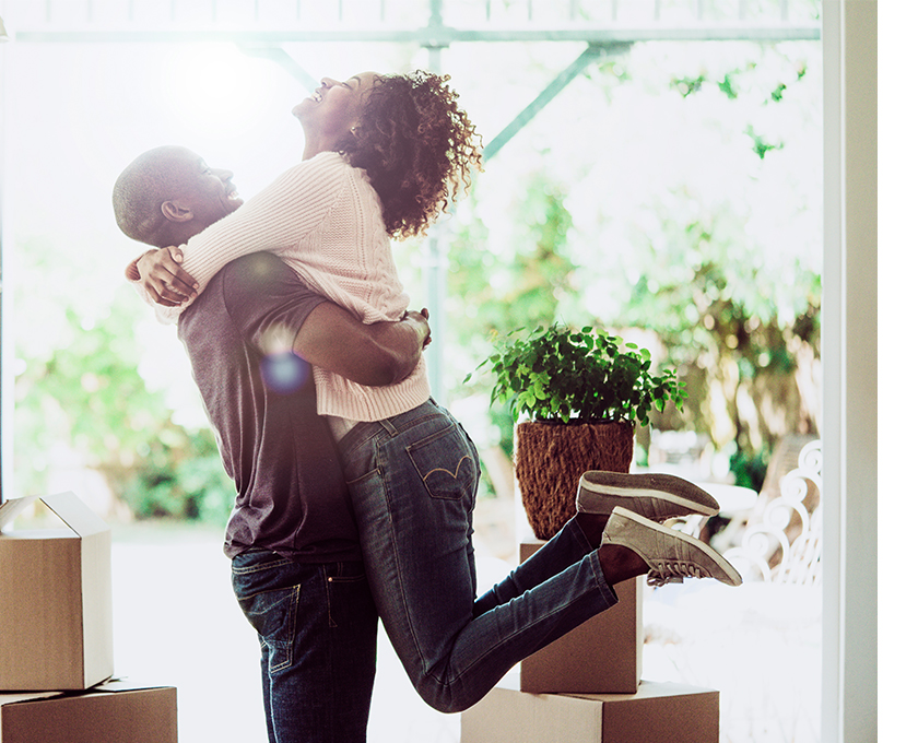 couple embracing near boxes and an open doorway woman has head back laughing