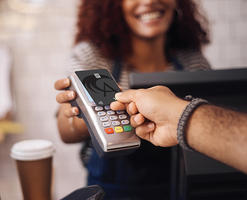 close up of man tapping his Allegacy Credit Card on a touchless card reader at a coffee shop