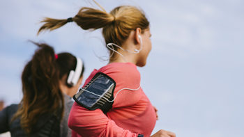 Two friends jogging with headphones and fitness trackers
