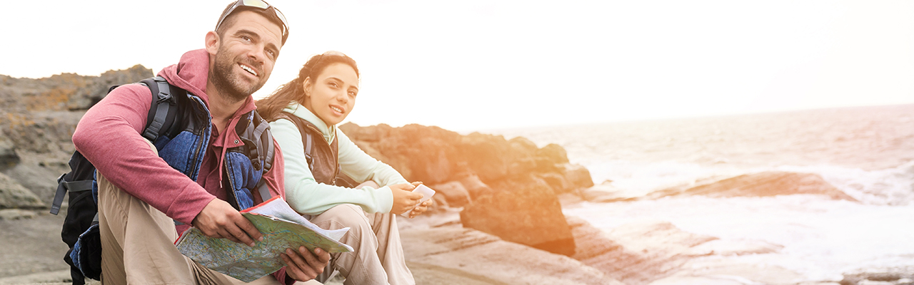 Young couple hiking, sitting on top of the rocks and enjoying the view