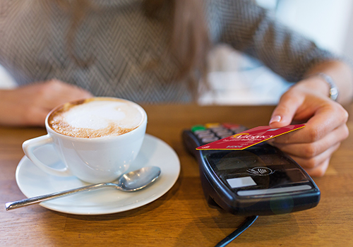 Woman using tap to pay with Allegacy debit card in coffee shop