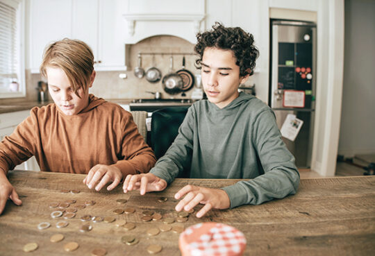 two teens in kitchen counting coins on countertop