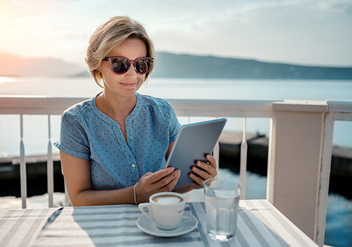 Mature woman managing finances on a tablet, while on vacation