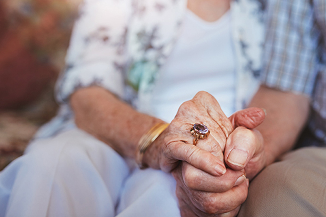 elderly couple holding hands