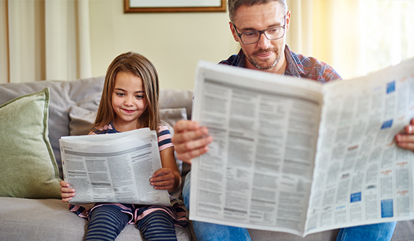 Child and man reading newspaper