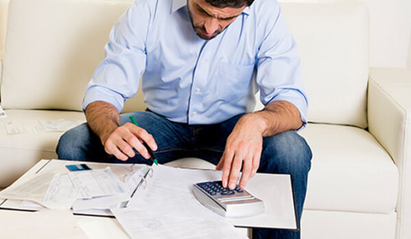 man on sofa using calculator