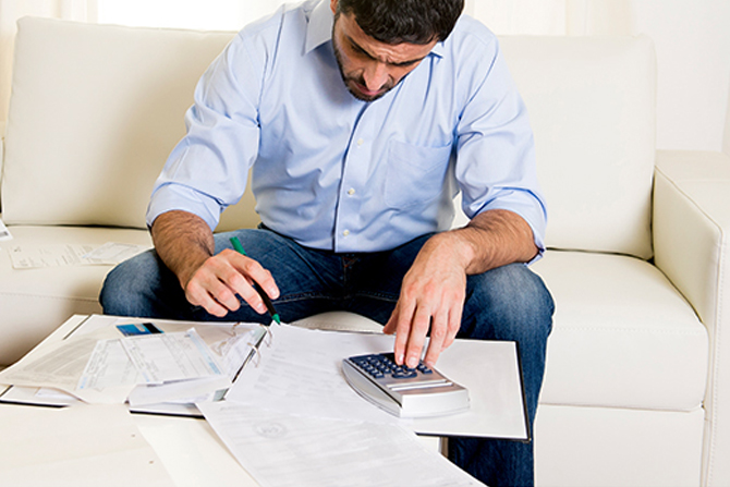 man on sofa using calculator