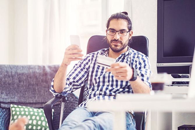 man using phone while holding a credit card