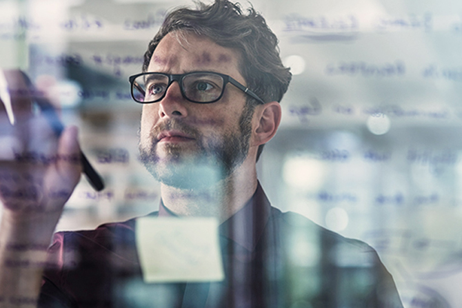 Man looking at glass wall with data