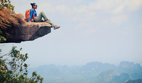 Young woman sitting on edge of mountain