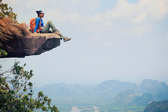Young woman sitting on edge of mountain