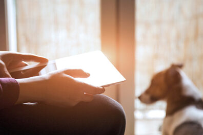 person on tablet with dog in the background