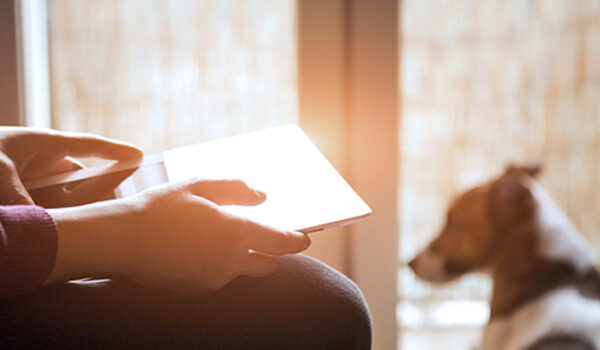 person on tablet with dog in the background