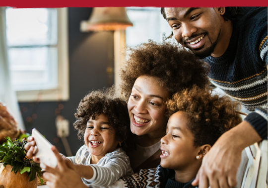 family with young children at dining room table taking a selfie