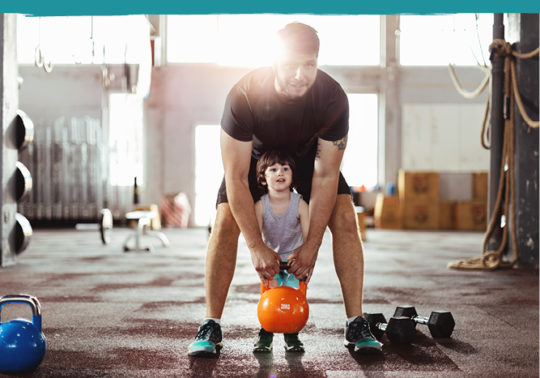 dad helping son lift weight in open gym