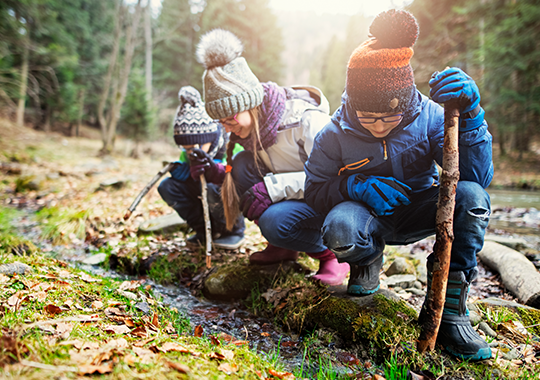 kids in winter coats and toboggans exploring the woods