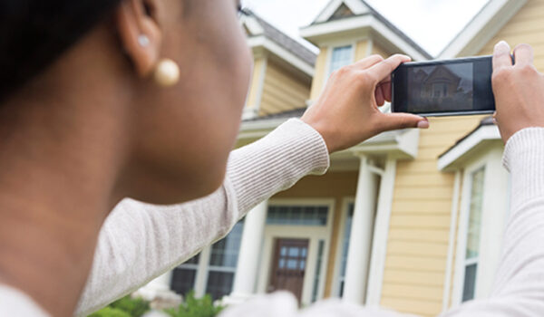 Woman photographing home with smartphone