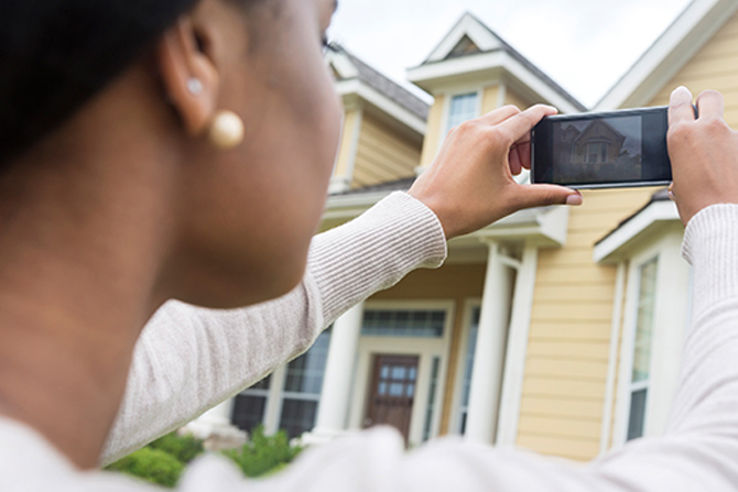 Woman photographing home with smartphone