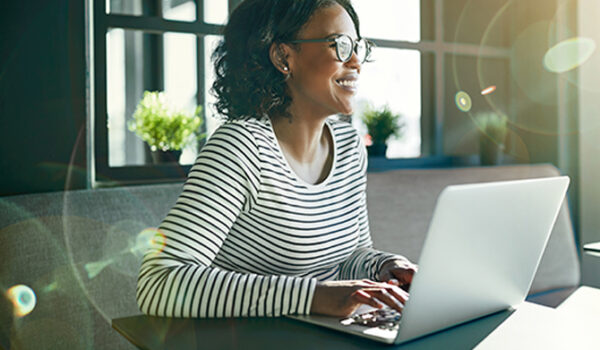 Smiling young African woman working online with her laptop