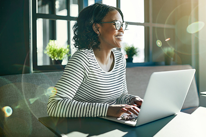 Smiling young African woman working online with her laptop