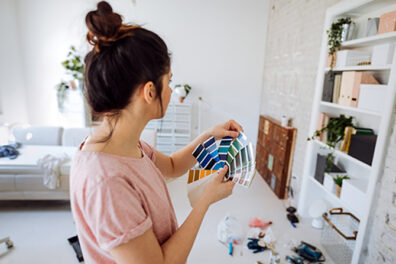 brunette with top knot looking at paint swatches in living room