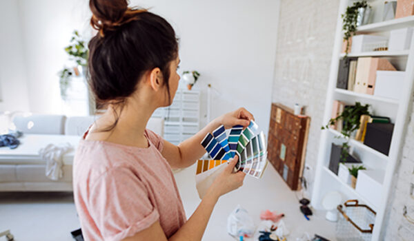 brunette with top knot looking at paint swatches in living room