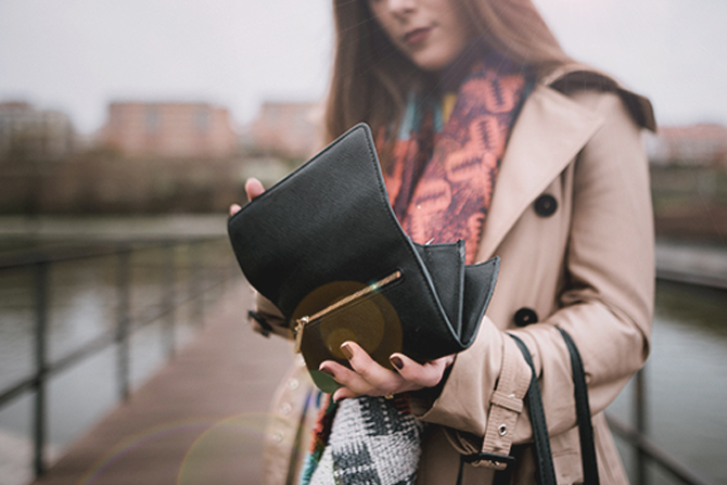 woman in trench coat and bright scarf checking wallet