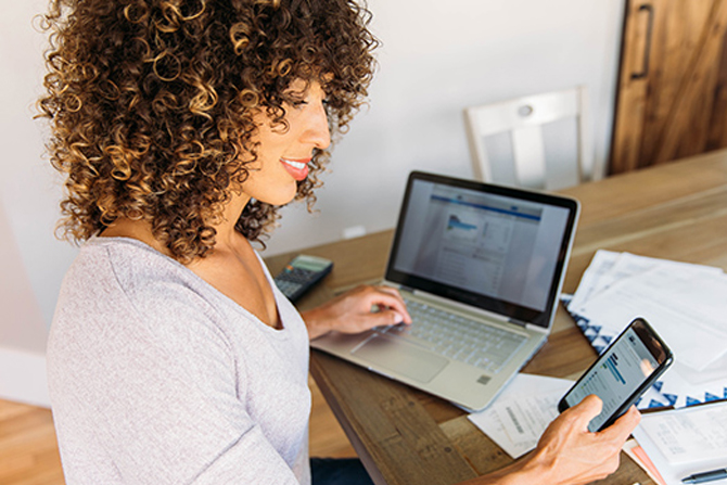 woman on smart phone in front of computer