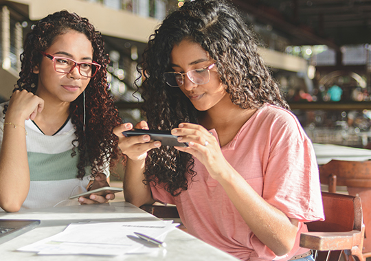 Two young girls taking picture on smartphone of barcode for payment of bills via online banking app