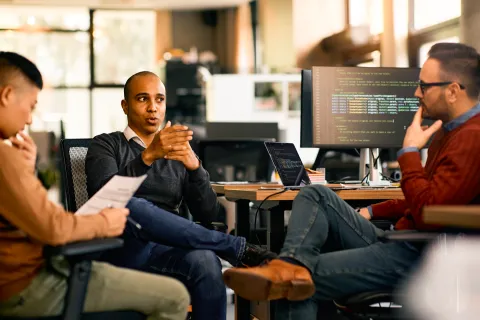 three seated men discussing at work